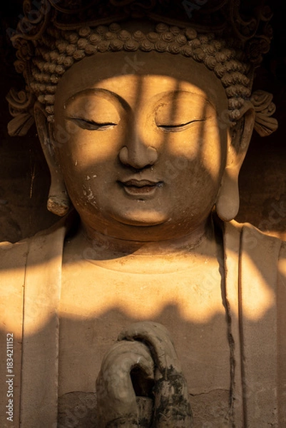 Fototapeta Seated Buddha Statue with Dappled Sunlight at Tapo Cliff Carvings in Anyue China