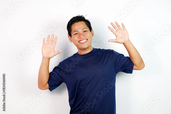Fototapeta Happy Man in Navy T‑Shirt Waves Hands Up With Friendly Smile Portrait