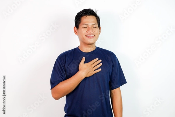 Fototapeta Smiling Man With Hand On Chest In A Calm, Peaceful Pose Wearing Navy T-Shirt