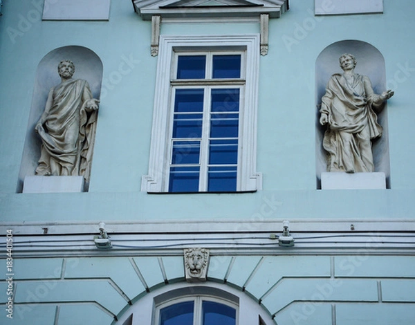 Fototapeta A light blue facade of a historic building in St. Petersburg, Russia. A building with two classical statues positioned in niches. for architectural, cultural, or travel-themed content