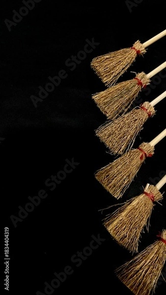 Obraz Mini witch brooms on black background, occult props, mystical composition, esoteric tools for magic and rituals