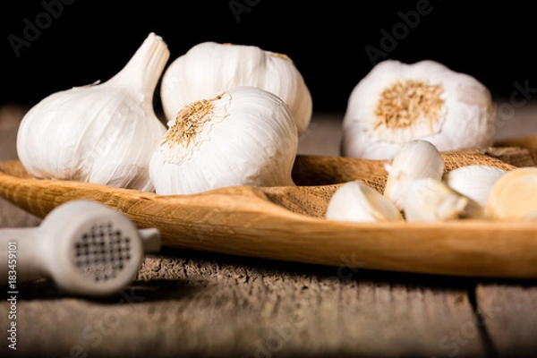 Fototapeta Garlic, Garlic cloves and Garlic bulb in vintage handmade wooden bowl. Front view.
