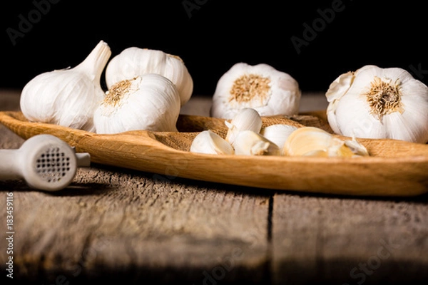 Fototapeta Garlic, Garlic cloves and Garlic bulb in vintage handmade wooden bowl. Front view.