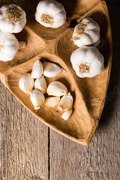 Fototapeta Garlic, Garlic cloves and Garlic bulb in vintage handmade wooden bowl. Top view.