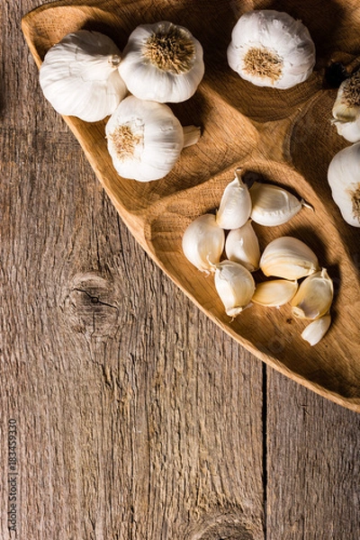 Fototapeta Garlic, Garlic cloves and Garlic bulb in vintage handmade wooden bowl. Top view.