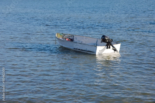 Obraz Small White Boat Floating on Calm Water, Seaside Scene with Gentle Waves in Gulfport, FL.
Sea water, reflecting soft light. The scene conveys solitude and peacefulness, ideal for travel, coastal lifes