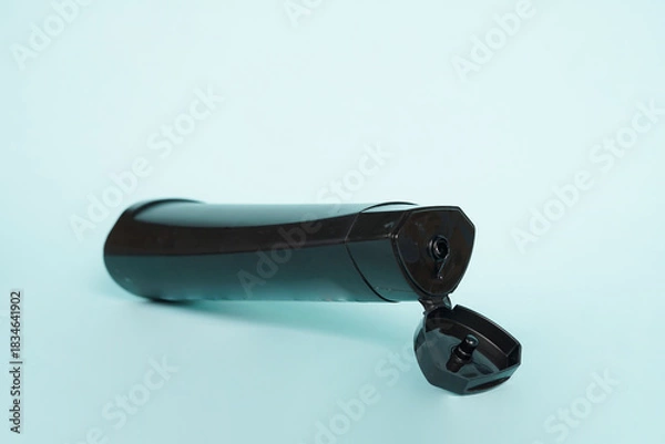 Fototapeta The shampoo bottle stands upright on a bright blue background, creating a clean and refreshing visual impression