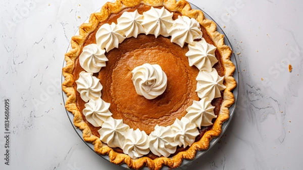 Fototapeta Overhead view of a pumpkin pie with whipped cream on a white surface