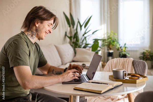 Obraz Young stylish man working on a laptop at home. Freelance concept, remote work.