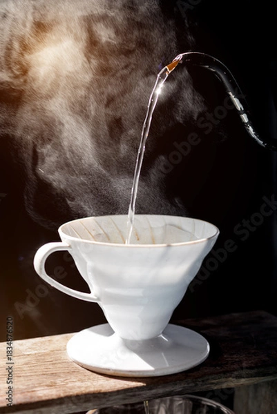 Obraz Pouring hot water into a ceramic coffee dripper with visible steam and dramatic sunlight, capturing the cozy, warm atmosphere of a relaxing morning routine.