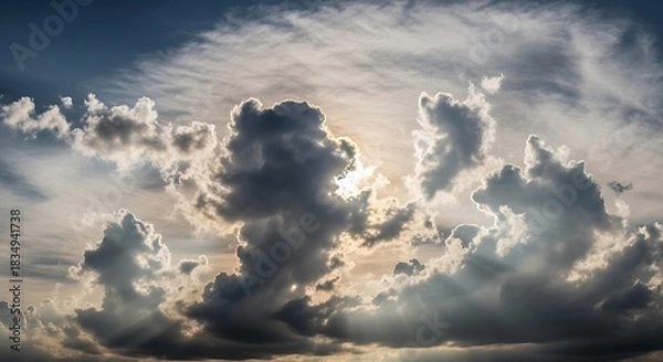 Fototapeta Sunbeams break through dramatic, dark, and light clouds.