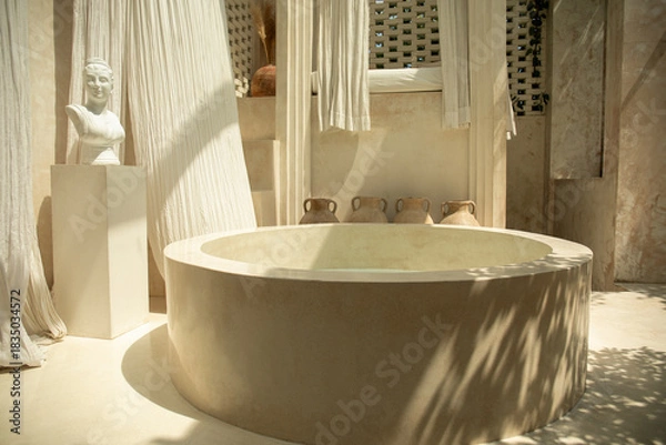Fototapeta An elegant spa area featuring a round stone tub and gentle textiles