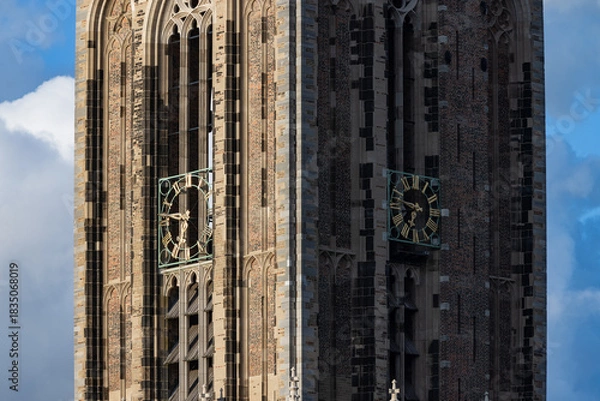 Fototapeta Close-up detail of the golden clock face and Gothic brickwork on the medieval Dom Tower in Utrecht, Netherlands, on a sunny day.