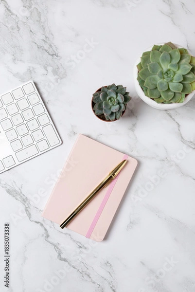 Fototapeta Vertical flat lay of succulents, white keyboard and pink notebook on a marble surface, minimalist and elegant workspace setup. Concept of modern workspace and creative lifestyle