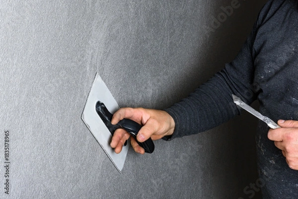 Fototapeta Worker using a float to smooth decorative pebble plaster on a wall.