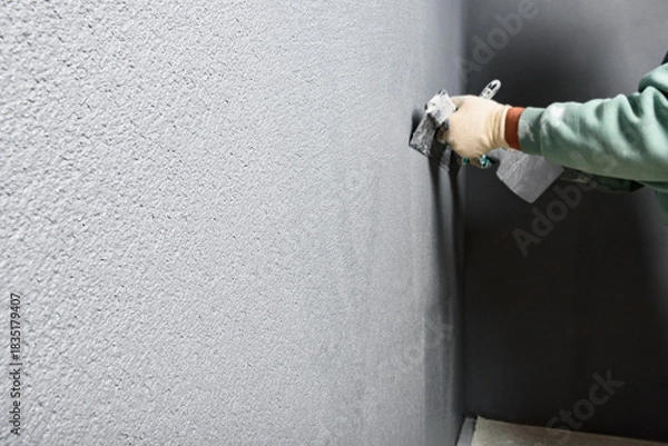 Fototapeta Applying concrete pebble plaster kornik using putty knife.