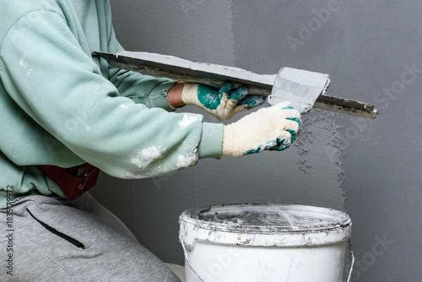 Fototapeta Applying concrete pebble plaster kornik using putty knife.