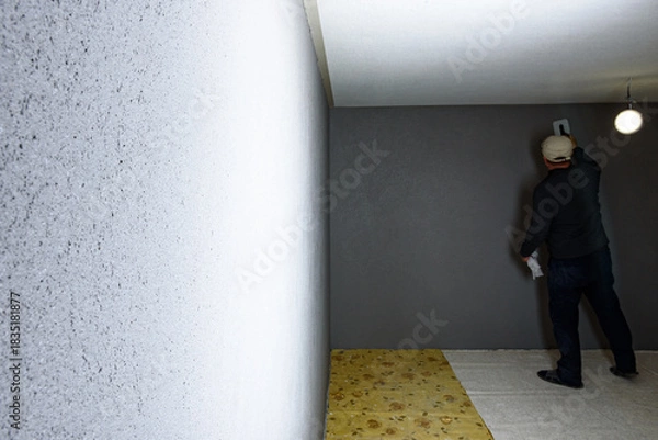 Fototapeta Worker using a float to smooth decorative pebble plaster on a wall.