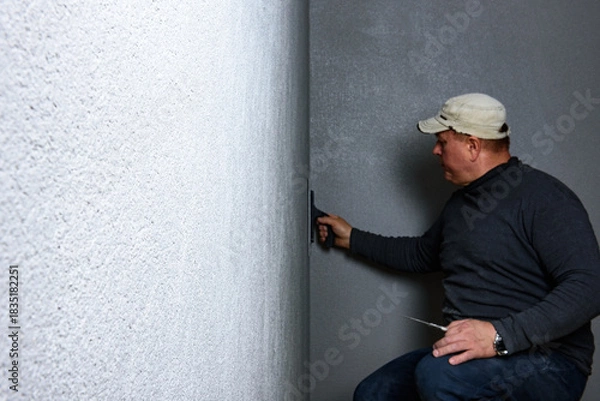 Fototapeta Worker using a float to smooth decorative pebble plaster on a wall.