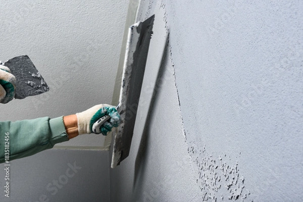Fototapeta Applying concrete pebble plaster kornik using putty knife.