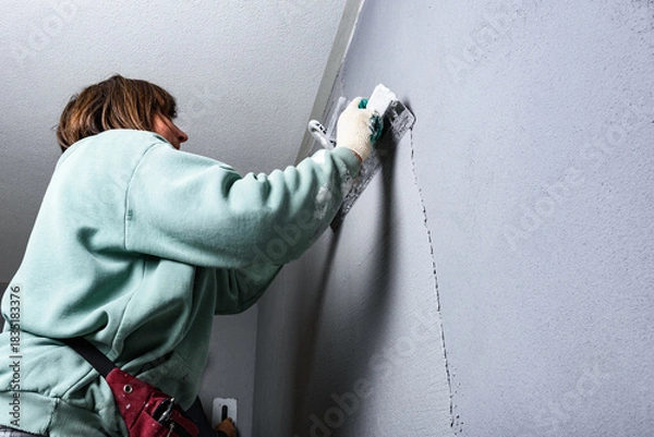 Fototapeta Applying concrete pebble plaster kornik using putty knife.