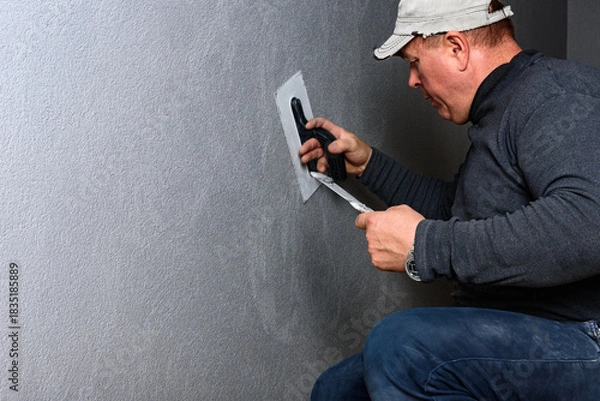 Fototapeta Worker using a float to smooth decorative pebble plaster on a wall.