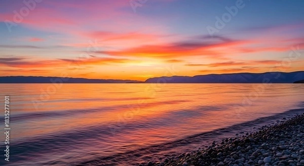 Fototapeta Vibrant sunset over tranquil lake with colorful sky and gentle waves.