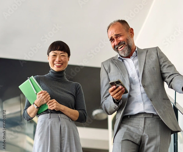 Fototapeta Portrait of mid aged businessman  and young businesswoman having a meeting or presentation and seminar standing in the office. Portrait of a young businesswoman  and businessman talking and walking do