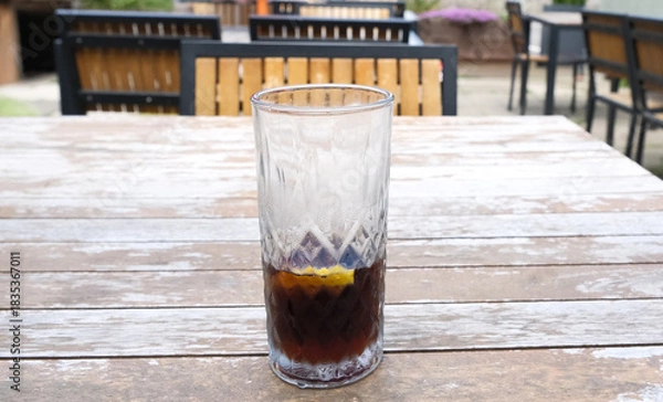 Fototapeta Close-Up of Cold Dark Soda Drink with Lemon Slice on Outdoor Wooden Table