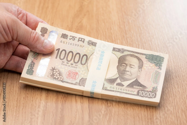 Obraz 一万円札の札束を手に持つ日本円の高額資金イメージ