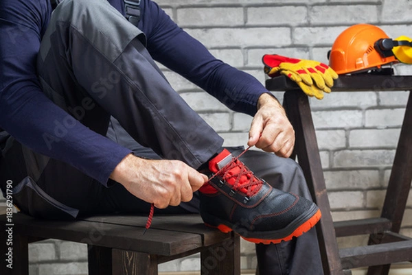 Obraz Worker putting on protective safety boots.