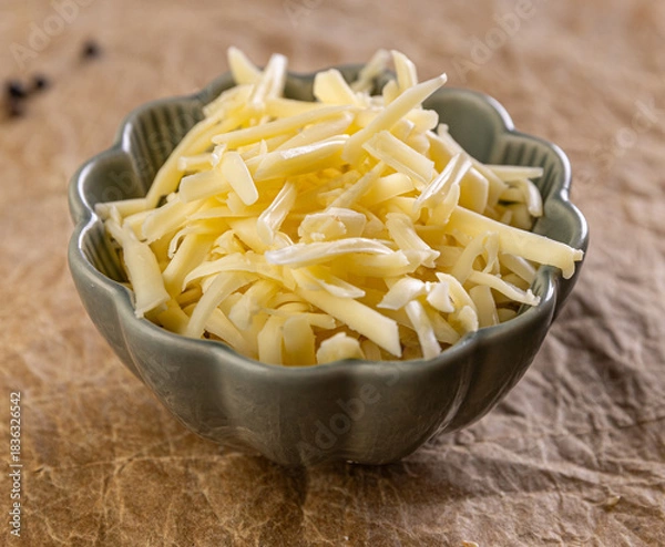 Fototapeta Shredded cheese filling a bowl