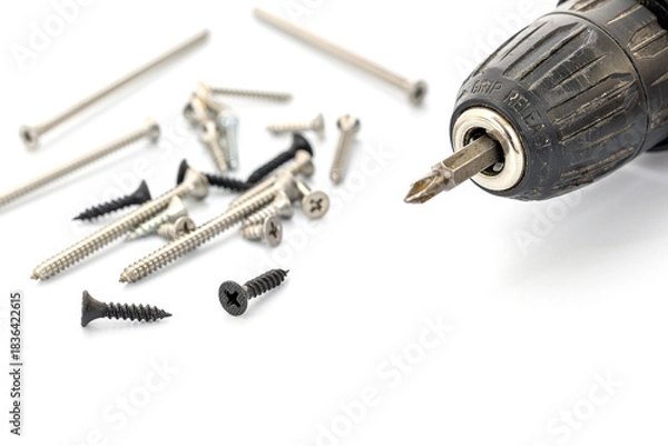 Obraz Close-up of a Black Cordless Drill Next to Assorted Screws on White Background
