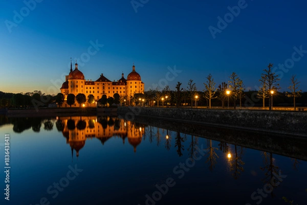 Fototapeta An enchanting twilight shot of Moritzburg Castle during the blue hour. The exterior of the Baroque castle is warmly illuminated