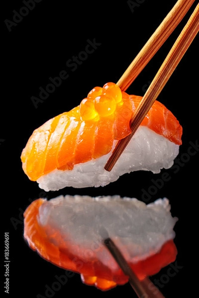 Obraz Salmon sushi nigiri in chopsticks isolated on black background with reflection.Close up.