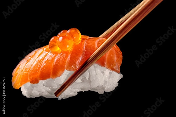 Fototapeta Salmon sushi nigiri in chopsticks isolated on black background.Close up.