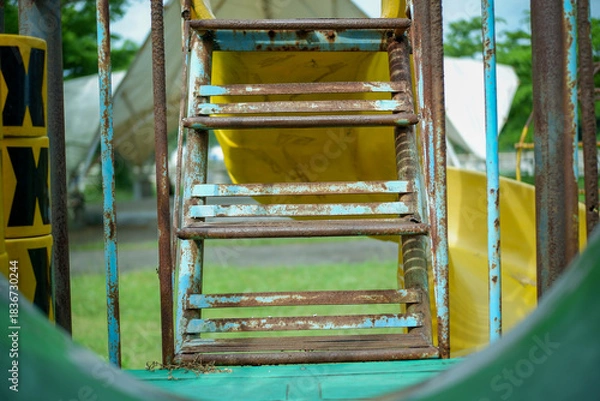 Fototapeta Rusty Metal Staircase On Old Playground Ladder With Weathered Feel And Colorful Background