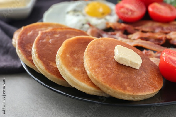 Fototapeta Plate with yummy pancakes, tomatoes, fried egg and bacon on table