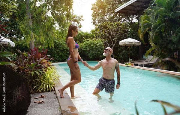 Obraz A man and woman enjoy each others company in a swimming pool