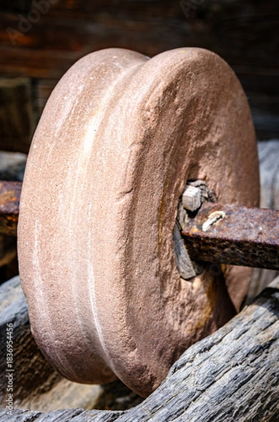 Fototapeta Historical stone wheel used for grinding grains in a rustic farming setting during daylight hours in an outdoor environment