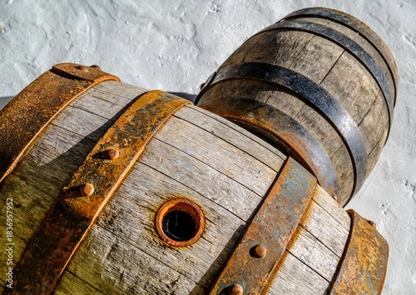 Fototapeta Old wooden barrels stacked against a stone wall in a historic cellar creating an atmosphere of tradition and time-honored craftsmanship