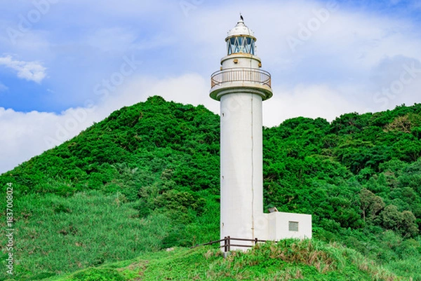 Obraz  梅雨の合間に輝く石垣島御神崎灯台と緑の丘の風景