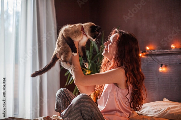 Obraz oung Woman hug Cat and sit on Bed in bedroom