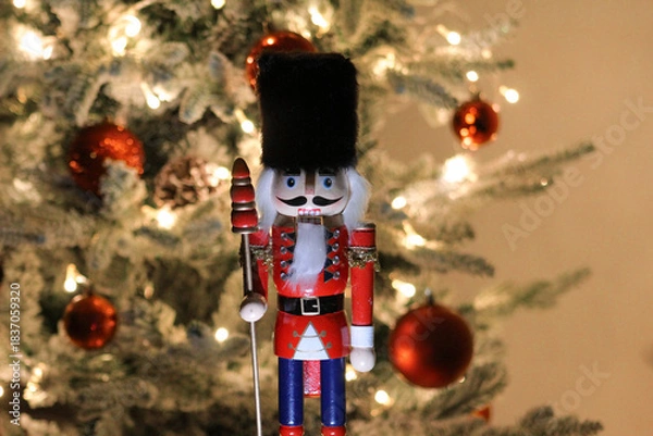 Obraz Wooden nutcracker figurine photographed in front of a decorated Christmas tree during a holiday display in Novi Sad on December 6, 2025.