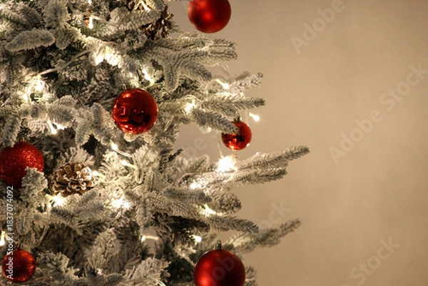 Obraz Beautiful snow-dusted Christmas tree with glowing lights and red ornaments, perfect for themes of warmth, celebration, and holiday charm.