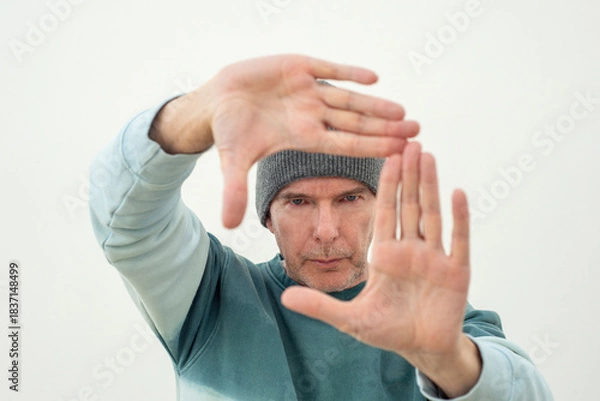 Obraz man in a knit hat making a frame with his hands, photographic framing