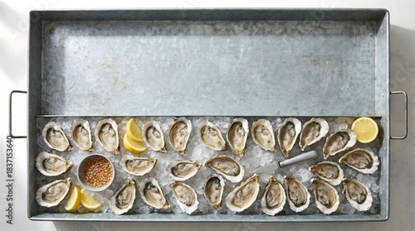 Fototapeta Raw oysters on the half shell served on ice in a metal tray with lemons.