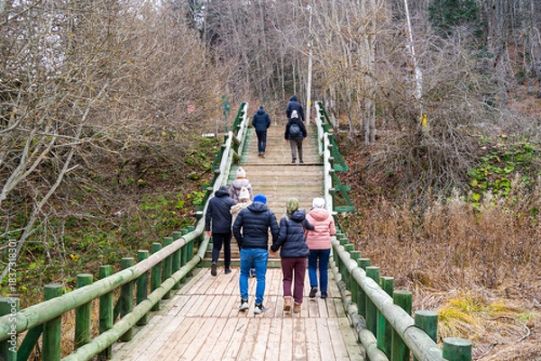 Fototapeta Group of Hikers Ascending a Wooden Boardwalk Through Autumn Woods