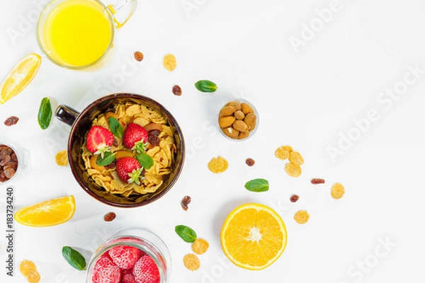 Fototapeta Cereal, morning breakfast, corn flakes, raisins, almonds, mint leaves, orange juice, strawberry, top view, white background, flat lay. The concept of healthy, proper nutrition, ditox.