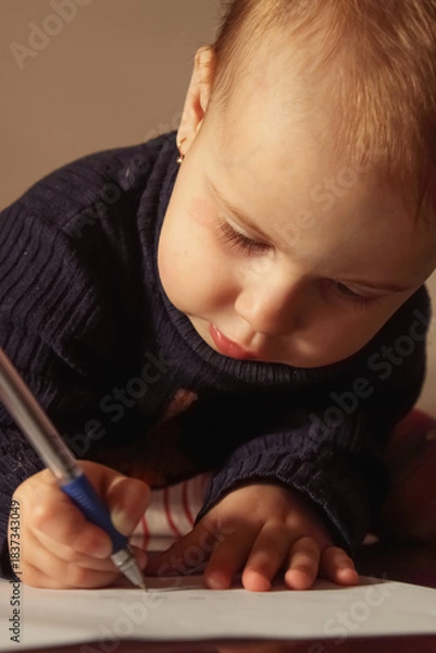 Fototapeta A toddler fully absorbed in the process of learning.